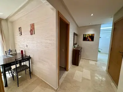 a dining room with a table and a hallway at Gueliz Twin Balcony Apartment F3 in Oulad Akkou
