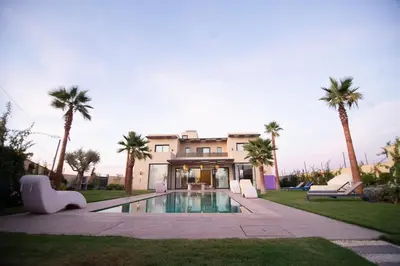 a house with a swimming pool and palm trees at Somptueuse villa 10personnes in Najem