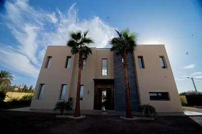 a building with two palm trees in front of it at Somptueuse villa 10personnes in Najem