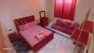a bedroom with a pink bed and a couch at شقق الراحة in Oulad Akkou