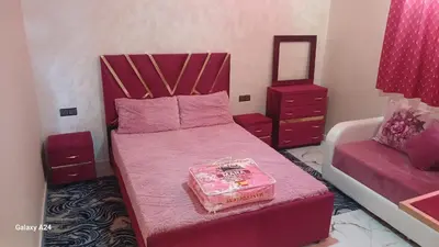 a bedroom with a pink bed and a mirror at شقق الراحة in Oulad Akkou