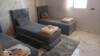 a room with three beds and a couch and a window at شقق الراحة in Oulad Akkou