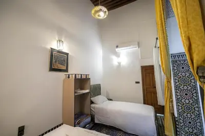 a small room with a bed and a mirror at Fes flower in Fès