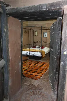 an open door to a bedroom with a bed at KASBAH DES MONTAGNS maisons d'hôtes la vallée des roses in Bou Tharar