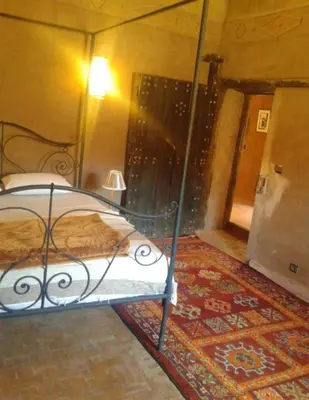 a bedroom with a bed and a rug on a floor at KASBAH DES MONTAGNS maisons d'hôtes la vallée des roses in Bou Tharar