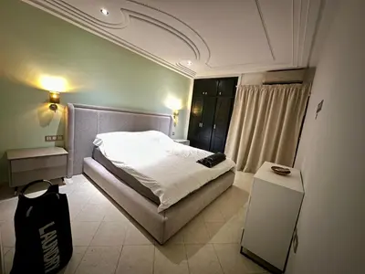 a bedroom with a bed and a black bag at Les Palmiers de l ile Jacob in Fès