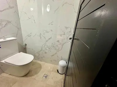 a bathroom with a toilet and a glass shower door at Les Palmiers de l ile Jacob in Fès