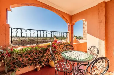 a balcony with a table and chairs and flowers at Atlas Suite Riad 3 Bedrooms near Marrakech in Tikoutar