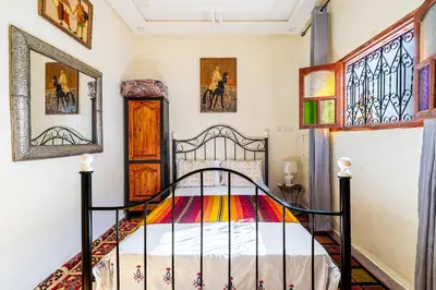 a bedroom with a bed and some paintings on the wall at Atlas Suite Riad 3 Bedrooms near Marrakech in Tikoutar