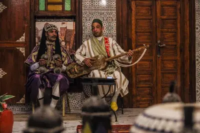two men sitting in a room with a guitar at Dar KAYED in Fès