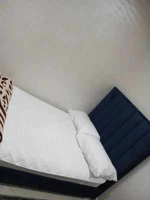 a bed with white sheets and a blue pillow at Appartement propre in Fès
