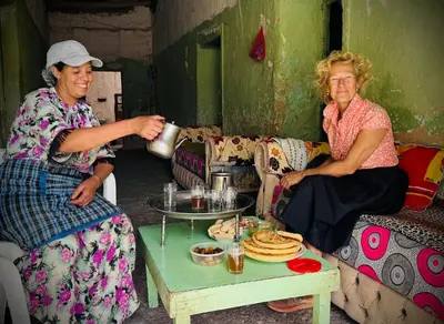 two women sitting on a couch with a coffee table at gite traditionnel berbère chez Naima in Lac Yasmins