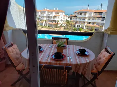 a table on a balcony with a view of a pool at Appartement front de mer à Sidi Rahal