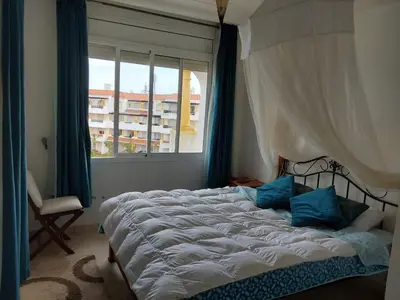 a bedroom with a large bed and a window at Appartement front de mer à Sidi Rahal
