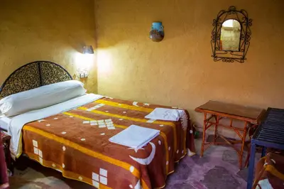 a bedroom with a bed and a table and a mirror at Riad Du Sud in Tamsahelt