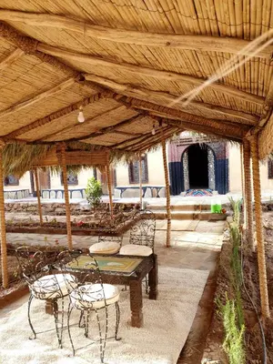 a patio with a table and chairs under a wooden roof at Riad Du Sud in Tamsahelt