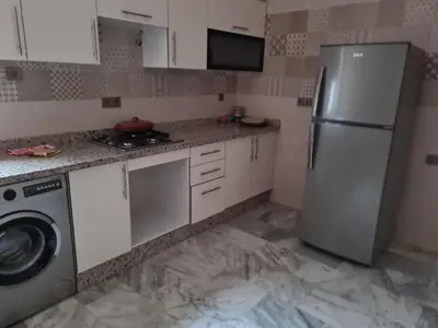a kitchen with white cabinets and a refrigerator at apparemment in Fès