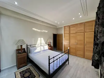 a bedroom with a bed with a black frame and wooden cabinets at Villa Fez Prestige with jacuzzi, Chic & peaceful in Fès