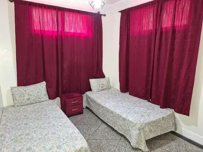 a bedroom with two beds and red curtains at Villa avec Piscine Meknes in Meknès