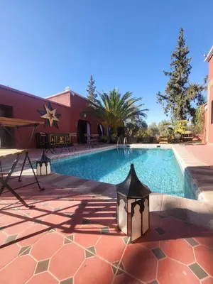 a swimming pool in front of a red building with a house at Ferme des Oliviers - Villa de Charme avec Vue Nature in Sfiani