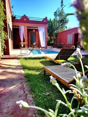 a backyard with a pool and a red building with a house at Ferme des Oliviers - Villa de Charme avec Vue Nature in Sfiani