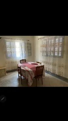 a dining room with a table and two chairs and curtains at Villa appartement jardin et piscine in Meknès