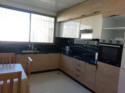 a kitchen with wooden cabinets and a sink and a table at Beautiful Apartment for Rent in Corniche de Rabat in Oulad Akkou