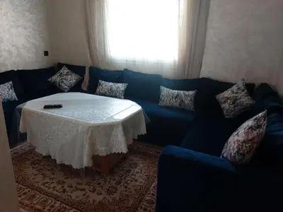 a living room with a blue couch with a table at Beautiful Apartment for Rent in Corniche de Rabat in Oulad Akkou