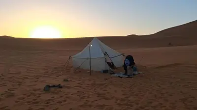 a tent in the desert with the sunset in the background at Isolé Bivouac Merzouga in Merzouga
