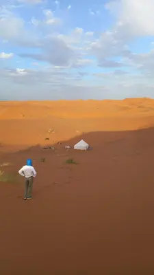 a man standing in the middle of a desert at Isolé Bivouac Merzouga in Merzouga