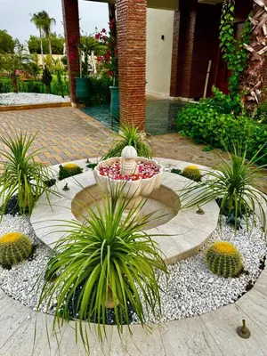 a garden with a fountain and plants in a courtyard at Villa Hasard Marrakech in Had Abdallah Rhiat