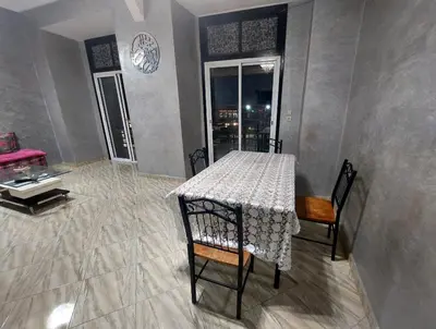 a table and chairs in a room with a table and a clock at Bright apartment with balcony in the center of FES in Fès