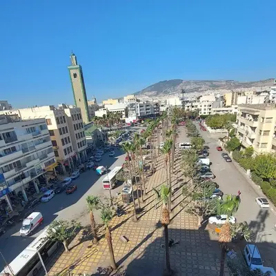 a city with a street with palm trees and buildings at Bright apartment with balcony in the center of FES in Fès