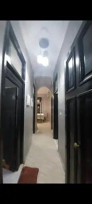 a hallway with black doors and a room with a table at Bright apartment with balcony in the center of FES in Fès