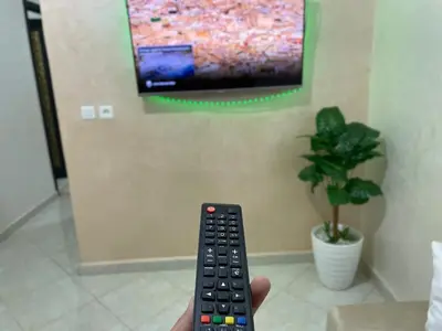 a person holding a remote control in front of a tv at Chic apartment in Fes luxurious and family friendly in Oulad Akkou