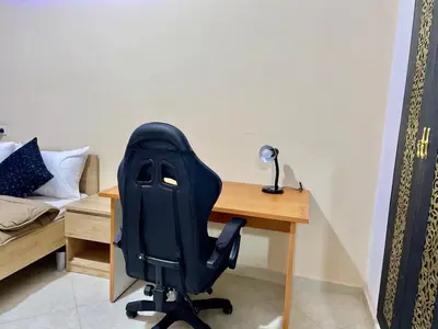 a desk with a black office chair next to a bed at Chic apartment in Fes luxurious and family friendly in Oulad Akkou