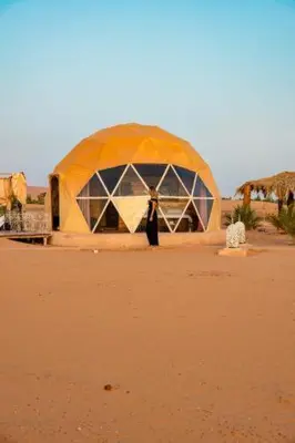 a person standing in front of a tent in the desert at Erg Chebbi Luxury Geodesic Camp in Merzouga