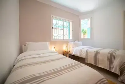 two beds in a white room with two windows at Modern Elegance & Moroccan Charm 5 min Hivernage in Oulad Akkou