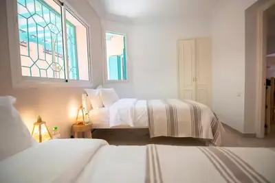 a white bedroom with two beds and a window at Modern Elegance & Moroccan Charm 5 min Hivernage in Oulad Akkou