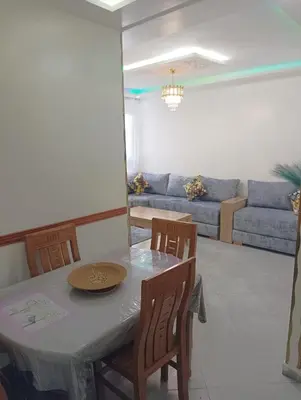 a dining room and living room with a table and chairs at مفتاح الساحل in Oulad Akkou