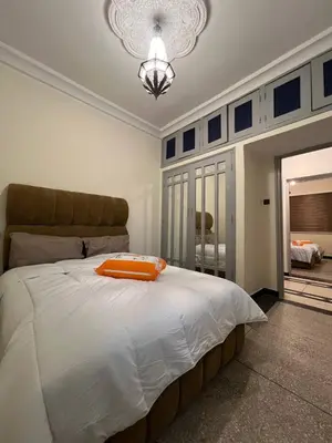 a bedroom with a large bed with an orange pillow on it at Desert Getaway Apartment In Ouarzazate in Ouarzazate