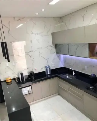 a kitchen with a black counter and white marble walls at Dar rahma in Khenifra