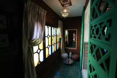 a room with a green door and windows and a table at Dar Laabi - Riad Aya in Fès