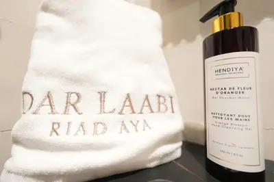 a white towel next to a bottle of carlabandridrid raveaqarma at Dar Laabi - Riad Aya in Fès