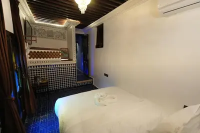 a bedroom with a white bed in a room with blue tiles at Dar Laabi - Riad Aya in Fès