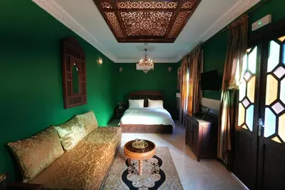 a bedroom with green walls and a bed and a couch at Dar Laabi - Riad Aya in Fès