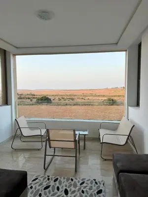 a living room with a table and chairs and a large window at Appartement à louer à BOUZNIKA OUED CHERRAT in Oulad Akkou