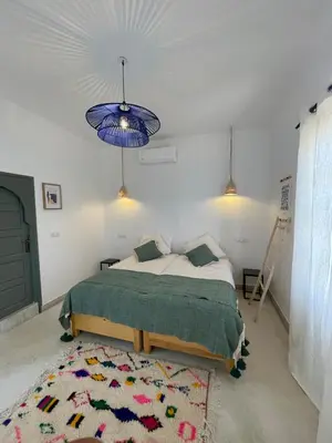 a bedroom with a bed and a blue ceiling at Maison El Alia in Merzouga