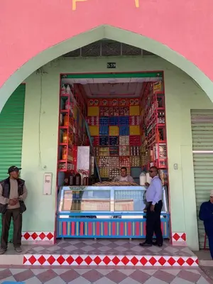 a store in a pink building with people standing outside at Maison El Alia in Merzouga