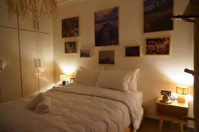 a bedroom with a white bed with pictures on the wall at Happiness Apartment in Ouarzazate